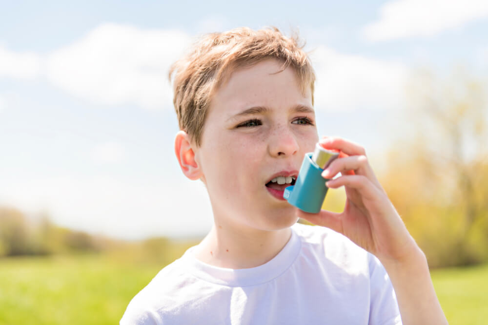 A child using inhaler for asthma outside in a park