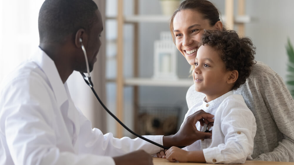 A doctor is examining a child with the child's mother present